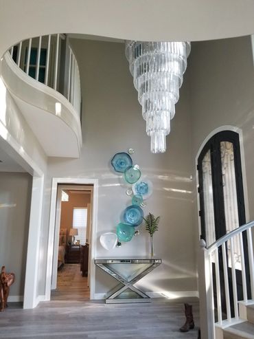 Elegant entryway with chandelier and glass wall art.