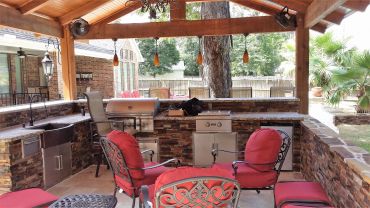 Cozy outdoor patio with red cushioned chairs and a grill.