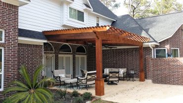Cozy backyard patio with wooden pergola and outdoor furniture.