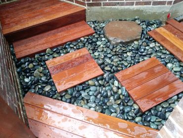Wooden steps over pebbles in a corner.