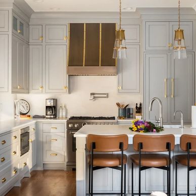 Elegant kitchen with white cabinetry, brass accents, and a cozy island seating area.