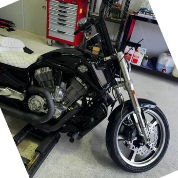 Black Harley-Davidson motorcycle with a custom white seat in a workshop.