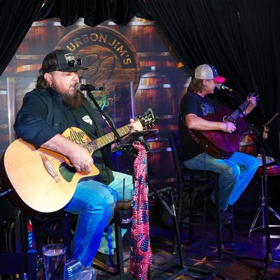 Two men performing live with acoustic guitars.