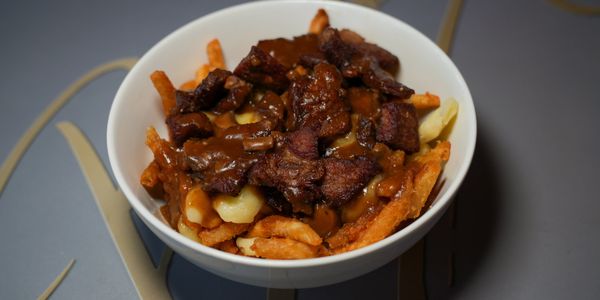 Bowl of fries topped with meat and gravy.