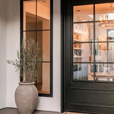 Modern black-framed glass door with a large ceramic planter outside.