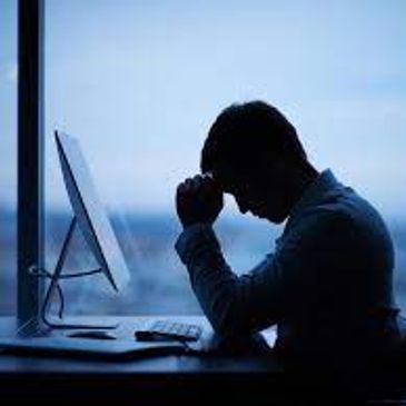 man at work looking dejected in front of a computer screen 