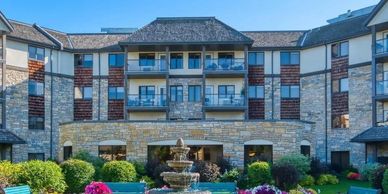 Stone building with balconies and a garden fountain in front.