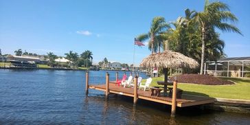 wooden dock, chairs and Tiki hut on a canal 