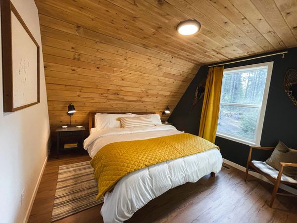 Cozy bedroom with wooden walls and yellow accents.