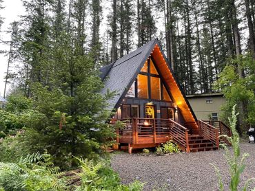 Cozy A-frame cabin in the woods with warm lights.