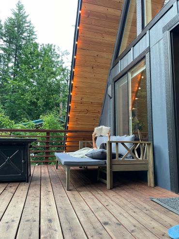Person reading on a wooden deck outside a cabin.