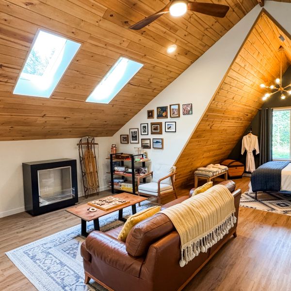 Cozy attic living space with wooden ceiling and skylights.