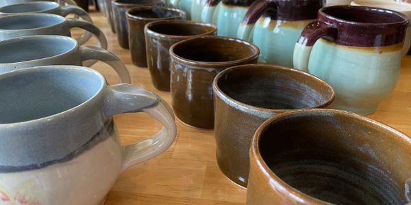 Completed mugs just unloaded from the glaze firing in the kiln.