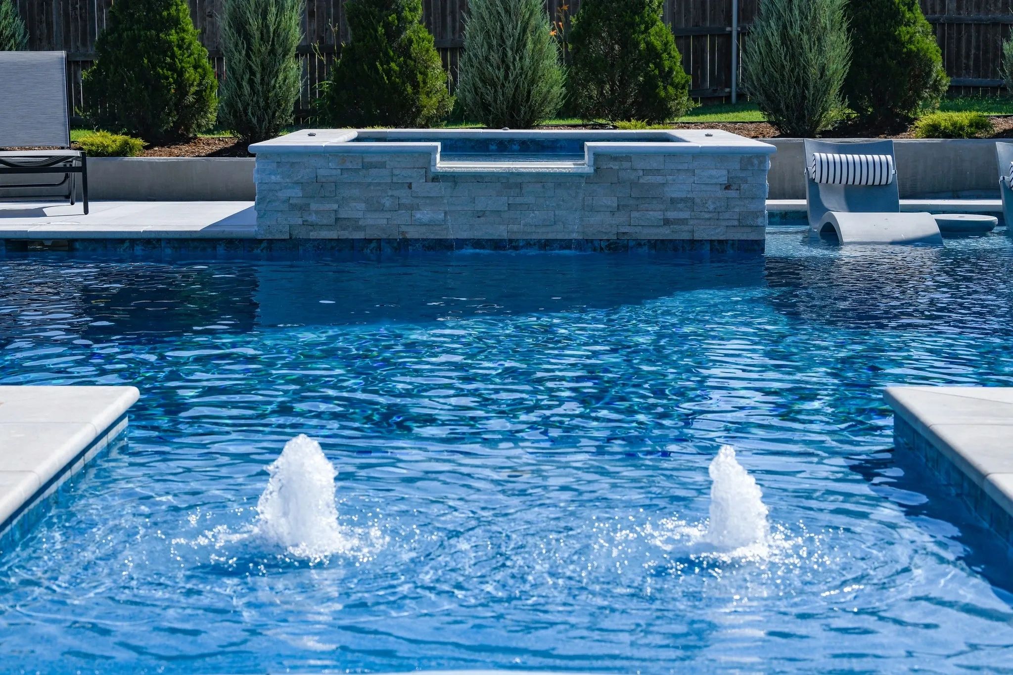 Gorgeous blue inground pool with waterfall from the spa.