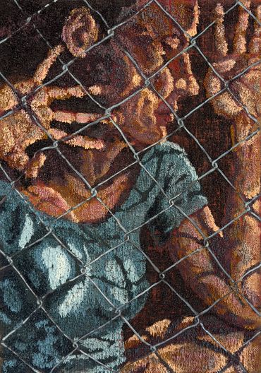 A person behind a chain-link fence with hands pressed against it.