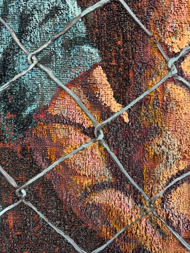Close-up of colorful textured graffiti behind a metal fence.
