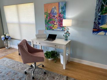 Cozy home office setup with a white desk and pink swivel chair.