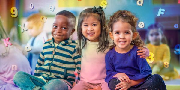 Three children sitting together smiling.