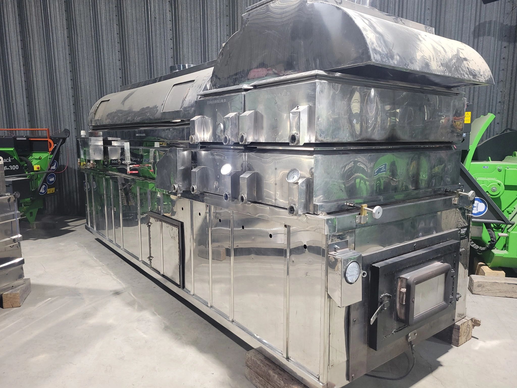 Large industrial stainless steel furnace or oven in a warehouse.