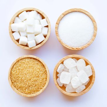 four wooden bowls filled with sugar cubes, white sugar, brown sugar and more sugar cubes.