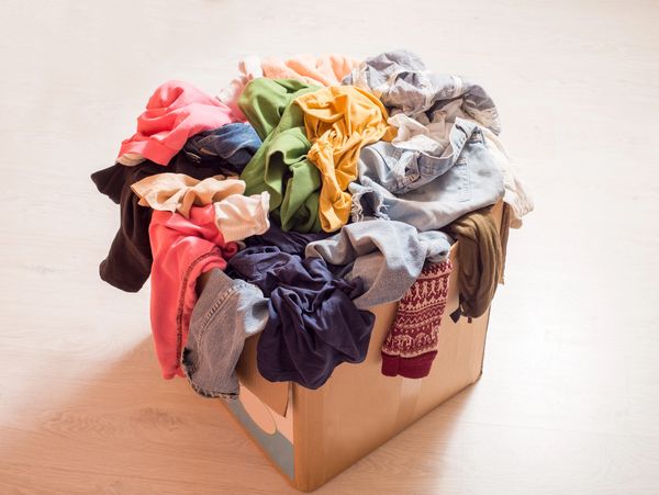 Pile of clothes in a large cardboard box. Sorting wardrobe and decluttering