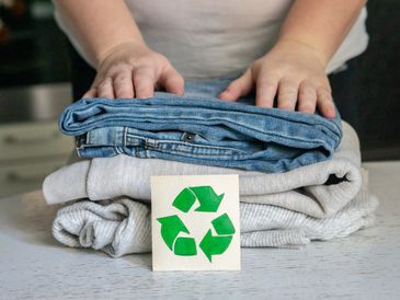 Garment recycling concept. A stack of clothes is on the recycling table.