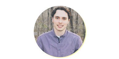 Young man smiling outdoors with a purple shirt.