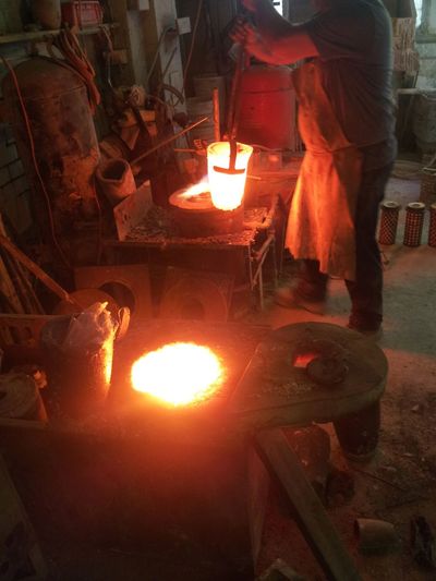 Molten bronze in crucible about to be poured into vacuum chamber