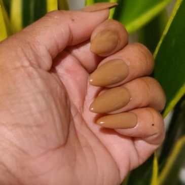 press on nails in the shape medium almond in a tan shade on a black woman's hand.