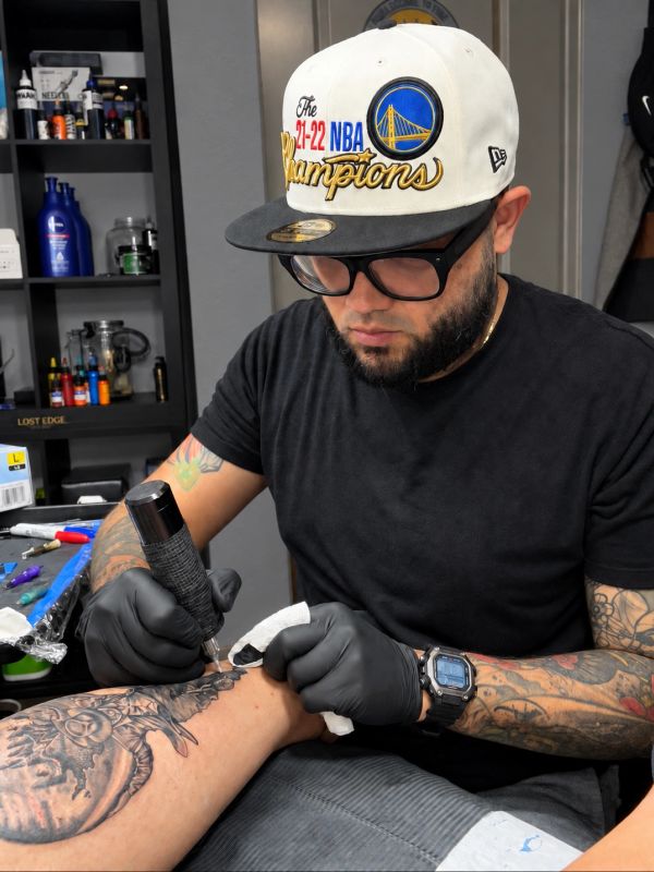 Tattoo artist working on a forearm tattoo.
