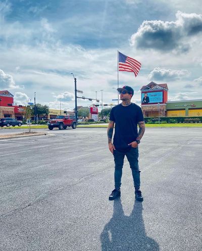Man standing in parking lot with American flag.