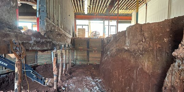 Contaminated soil being excavated beneath a building that is being structurally supported.