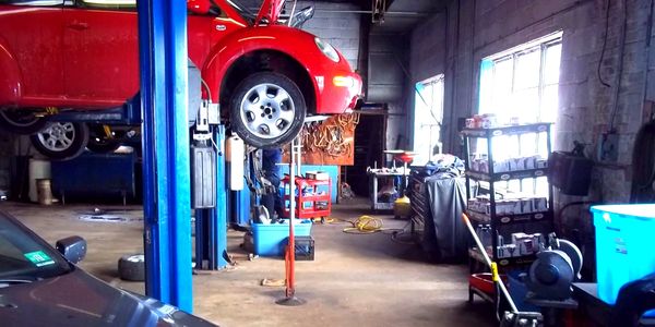 Interior of a garage with hydraulic lifts and suspended vehicles.