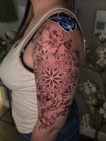 Intricate floral and geometric tattoo with a blue butterfly on upper arm.