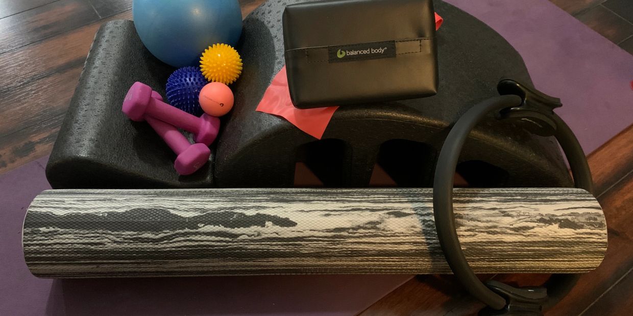 A collection of fitness and recovery tools including balls, dumbbells, foam roller, and yoga ring.