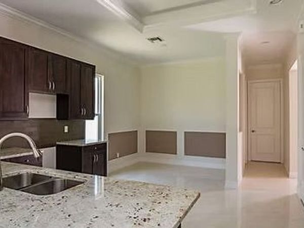 Empty kitchen space with granite countertop and dark cabinets.
