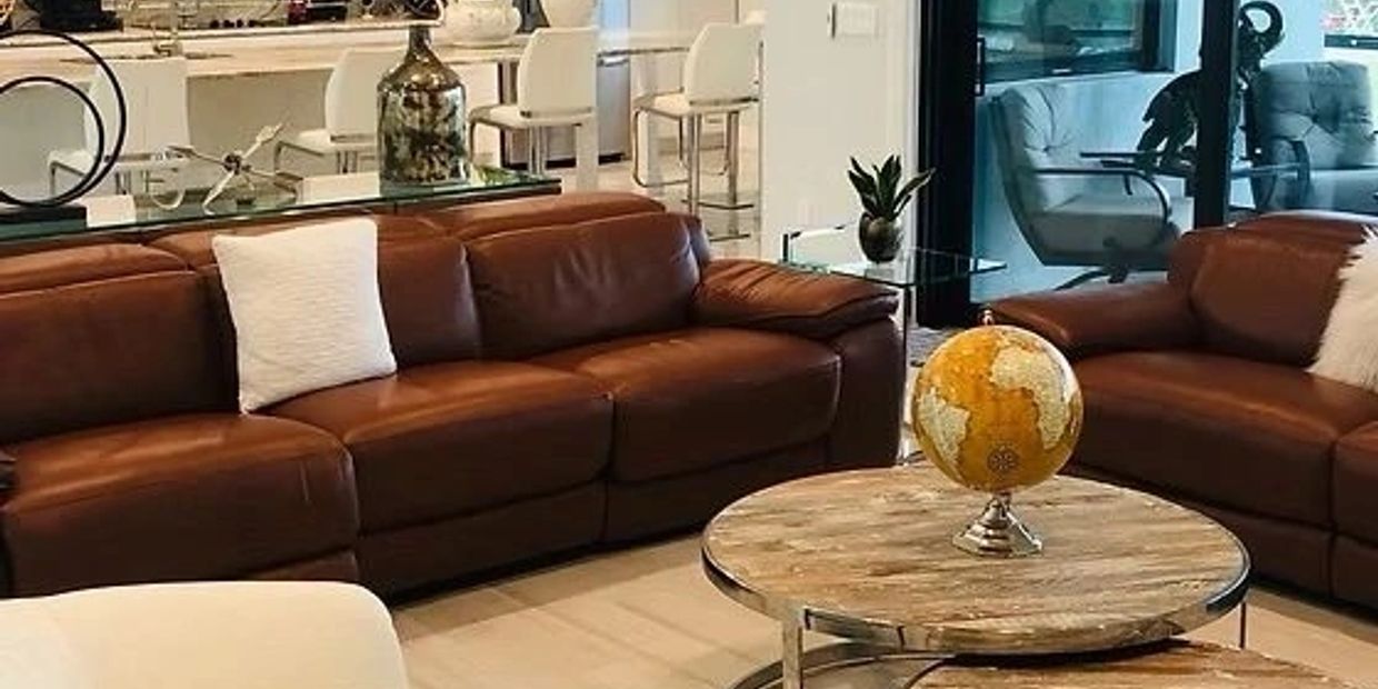 Modern living room with brown leather sofas and round wooden coffee tables.