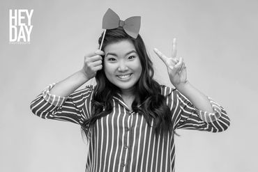 An young asian woman posing for a black and whie photobooth photo while making a peace sign with one