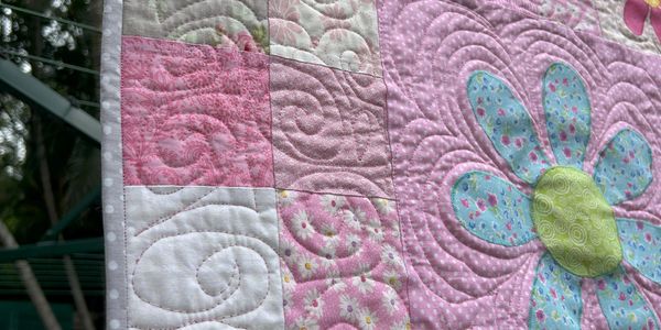 Colorful floral quilt hanging outside on a clothesline.