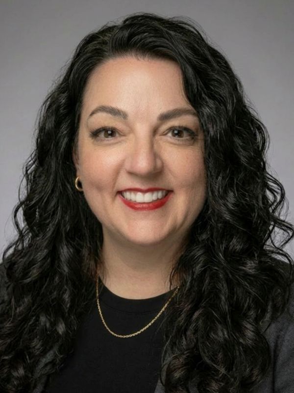 Smiling woman with curly black hair and red lipstick.