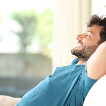 A man relaxing on a couch with a peaceful smile.