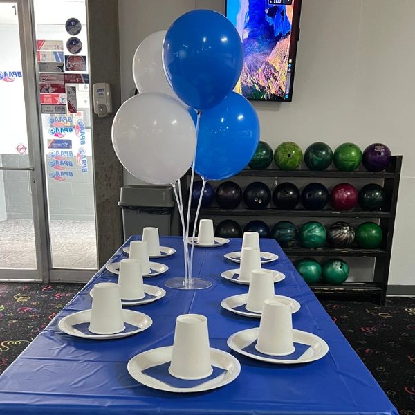 Table set for a bowling party with balloons and paper plates.