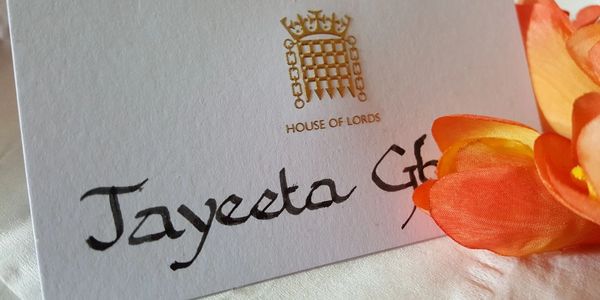 A House of Lords card with handwritten name and an orange flower.