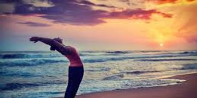 Sunset on ocean with healthy woman stretching. 