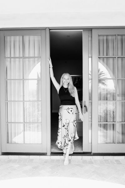 Smiling woman standing barefoot in doorway.