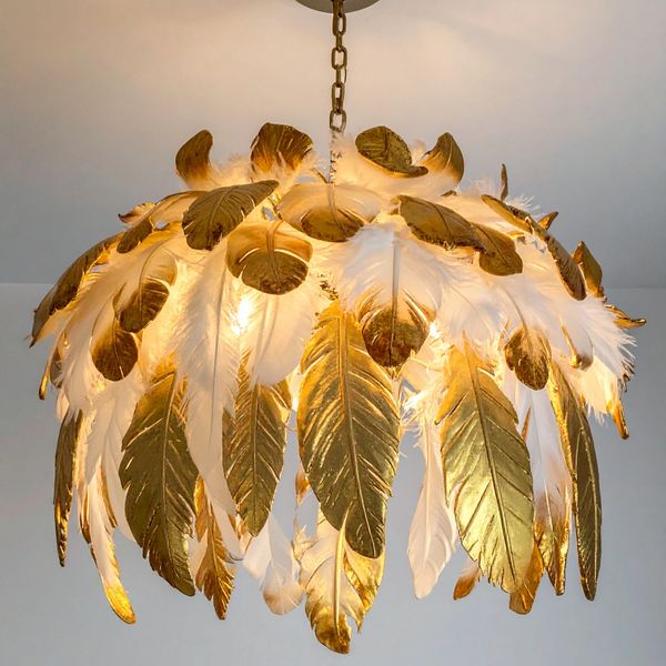 Elegant chandelier adorned with white and gold feathers hanging from the ceiling.