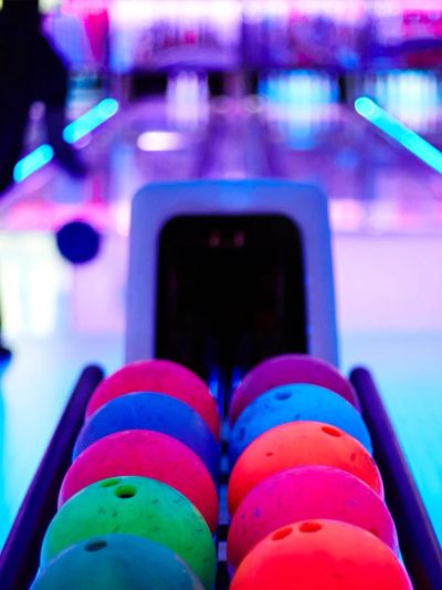 Colorful bowling balls with a player in the background.