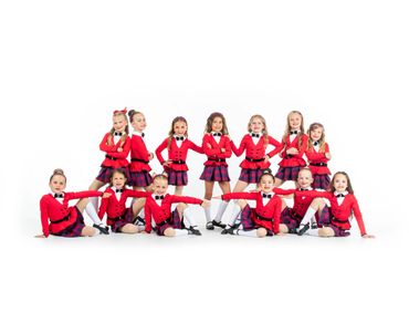 A group of young girls in red and plaid dance costumes posing in formation.