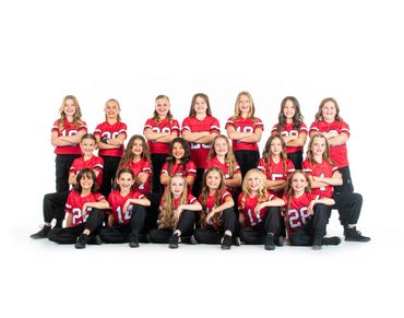 Youth girls' sports team in red jerseys and black pants posing confidently.