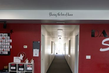 Dance studio hallway with costumes, trophies, and motivational text.